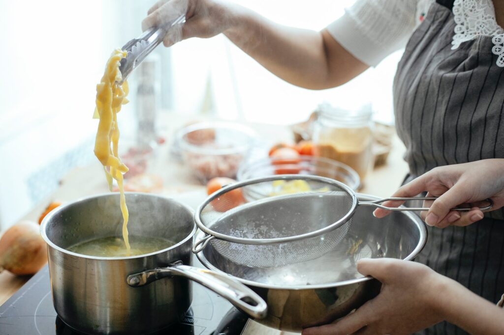 crop cooks preparing pasta in kitchen